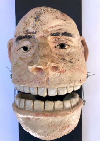 Gesicht/Kopf aus Ton mit übermäßig breitem Grinsennund dominaten Zahnreihen