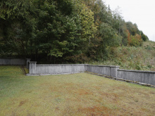 Eisenerz Mahnmal; Wald im Hintergrund, halbhohe Mauer, davor Wiese